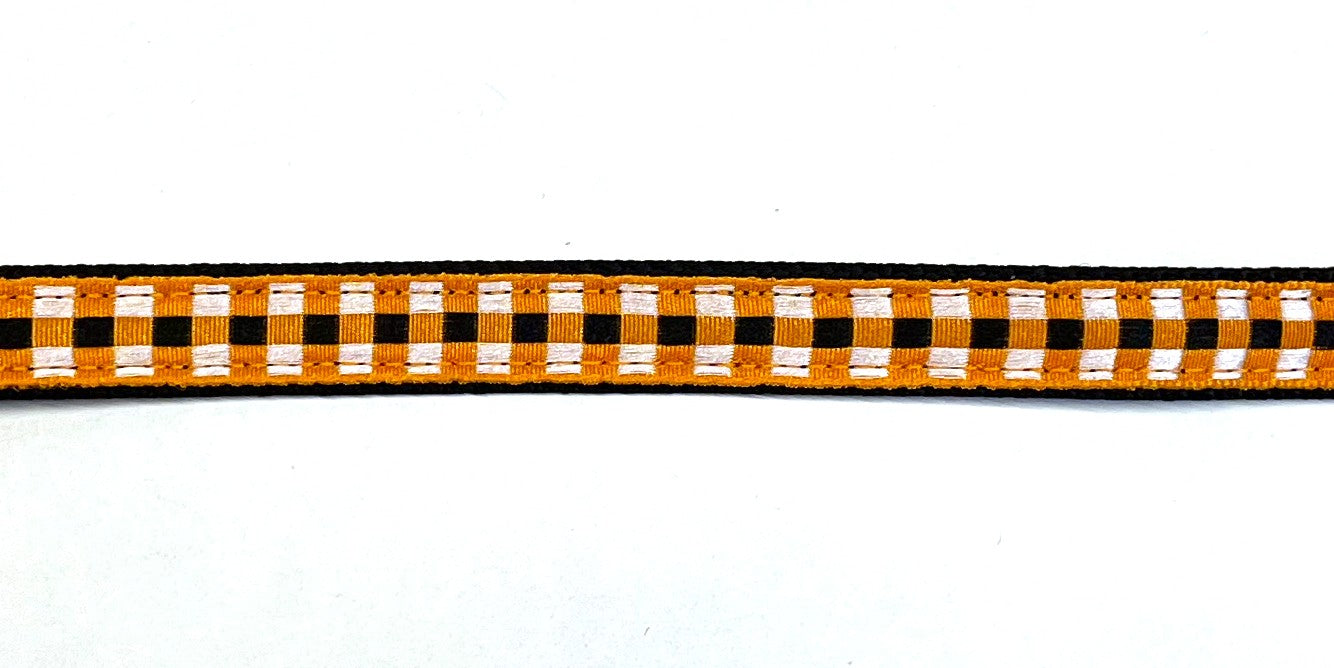 Black webbing dog collar with orange, black, and white plaid ribbon