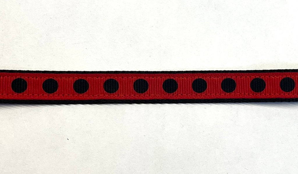 Red ribbon with black polka dots on black webbing dog collar
