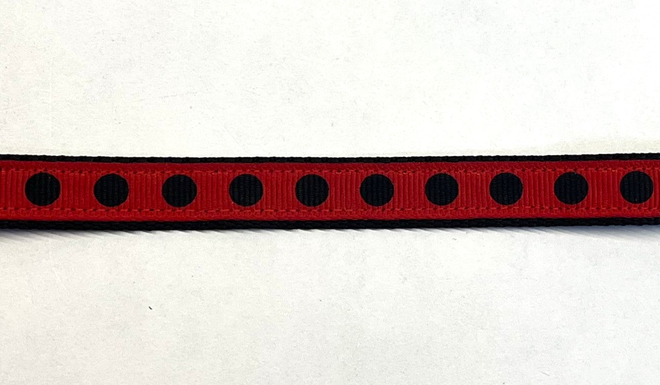 Red ribbon with black polka dots on black webbing dog collar
