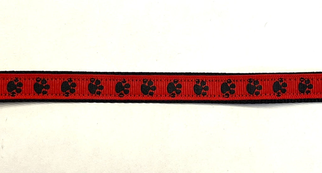 Red ribbon with black paw prints on black webbing dog collar