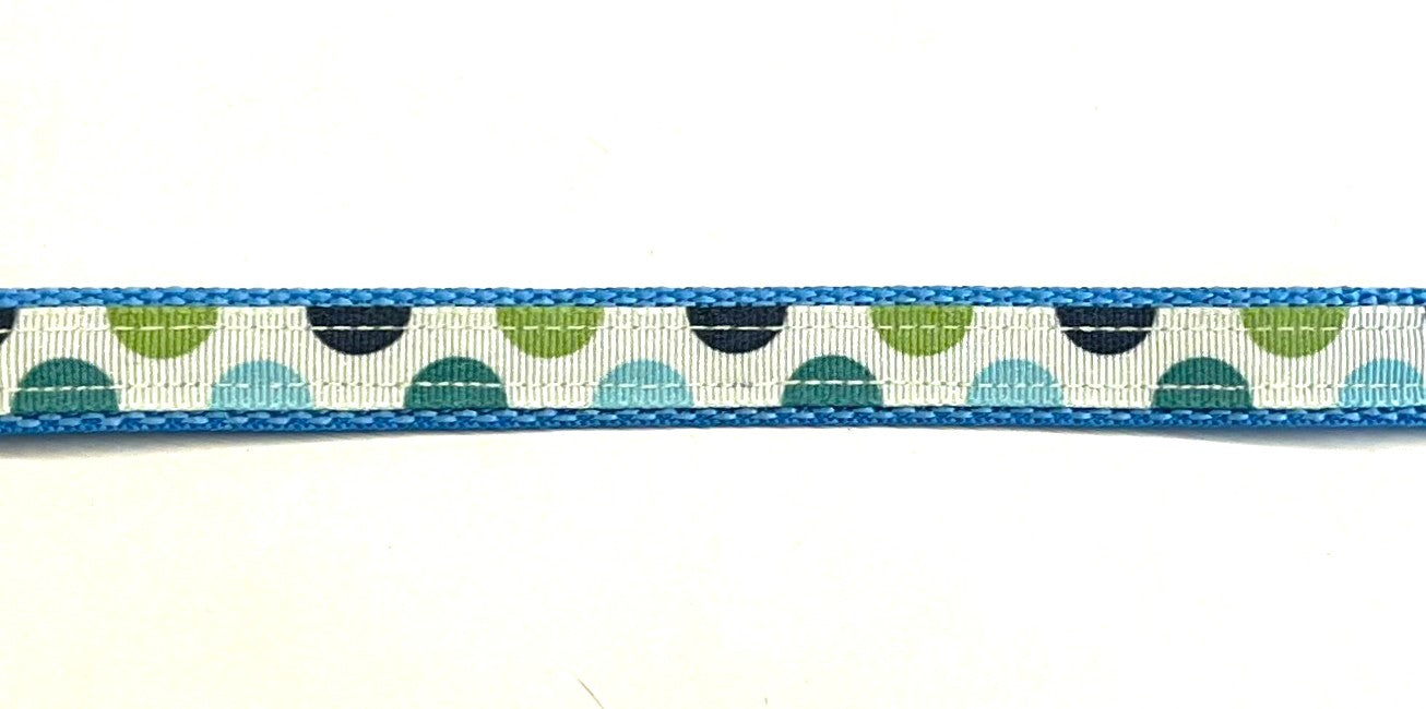 White ribbon with blue, green, teal, and navy half circles on light blue webbing dog collar
